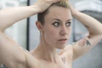 Feche a mulher com tatuagens e mãos no cabelo — Fotografia de Stock
