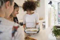 Happy young women friends cooking in kitchen — Stock Photo