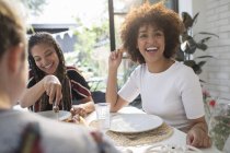 Glückliche junge Freundinnen genießen das Mittagessen am Esstisch — Stockfoto