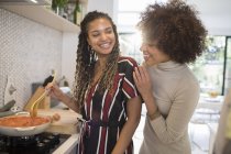 Happy young women friends cooking at stove in kitchen — Stock Photo