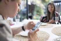 Giovane donna con smart phone al tavolo da pranzo — Foto stock