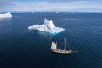 Корабль проплывает мимо айсберга на солнечно-голубом атлантическом океане — стоковое фото