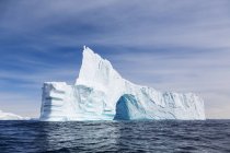 Majestuoso iceberg con arco sobre el soleado océano Atlántico azul Groenlandia - foto de stock