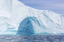 Величественная арка айсберга над солнечным голубым океаном Гренландия — стоковое фото