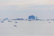 Maestoso arco iceberg in lontananza sulla tranquilla Groenlandia dell'Oceano Atlantico — Foto stock