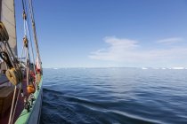 Barco navegando hacia icebergs en el tranquilo y soleado Océano Atlántico Groenlandia - foto de stock
