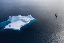 Ship sailing past majestic iceberg formation on blue Atlantic Ocean Greenland — Stock Photo