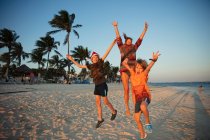 Portrait carefree family jumping for joy on tropical beach Mexico — Stock Photo