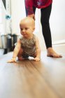 Cute baby girl crawling on hardwood floor — Stock Photo