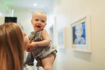 Mãe segurando feliz bonito bebê menina no corredor — Fotografia de Stock