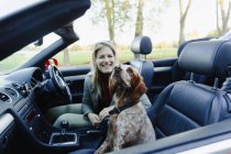 Портрет счастливой женщины, катающейся в кабриолете с собакой — стоковое фото