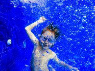 Porträt verspielter Junge schwimmt unter Wasser in blauem Pool — Stockfoto