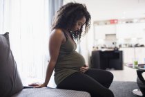 Спокойная молодая беременная женщина касается желудка — стоковое фото