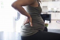Fechar a mulher grávida esfregando dor de volta — Fotografia de Stock