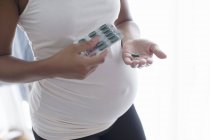 Крупним планом вагітна жінка бере вітаміни — стокове фото