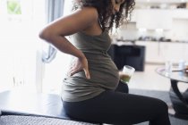Молодая беременная женщина пьет зеленый смузи и сдерживает — стоковое фото