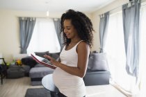 Молода вагітна жінка використовує цифровий планшет — стокове фото