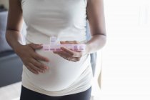 Закройте беременную женщину коробкой с таблетками, принимающими витамины — стоковое фото