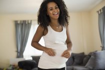Portrait happy young pregnant woman measuring stomach — Stock Photo