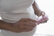 Close up pregnant woman with pill box taking vitamins — Stock Photo