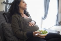 Tired young pregnant woman eating salad — Stock Photo