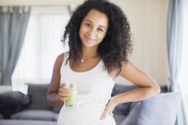 Retrato feliz joven embarazada bebiendo batido verde saludable - foto de stock