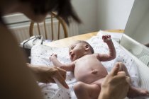 Mother changing diaper of newborn baby son on changing table — Stock Photo