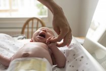 Mother holding hands with crying newborn baby son on changing table — Stock Photo