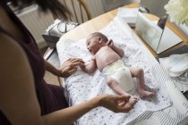 Mutter wechselt Windel ihres neugeborenen Sohnes auf Wickeltisch — Stockfoto