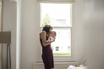 Mother kissing newborn baby son in window — Stock Photo