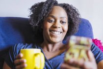 Cierre a una mujer feliz tomando té y utilizando teléfonos inteligentes - foto de stock