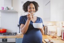 Portrait femme enceinte heureuse manger dans la cuisine — Photo de stock