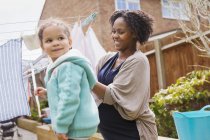 Happy pregnant woman and daughter hanging laundry on clothesline — Stock Photo