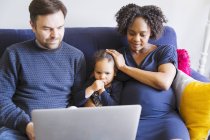 Multicultural family using laptop on sofa — Stock Photo