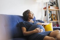 Ніжна вагітна жінка розслабляється на дивані — стокове фото