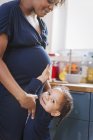 Portrait cute daughter touching pregnant mother stomach — Stock Photo