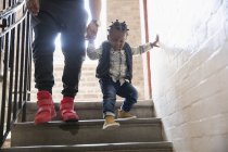 Отец помогает маленькому сыну спуститься по лестнице — стоковое фото