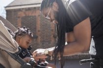 Happy father fastening toddler son in stroller — Stock Photo