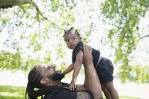 Играющий отец держит маленького сына в парке — стоковое фото