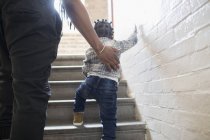 Father helping toddler son climb stairs in stairwell — Stock Photo