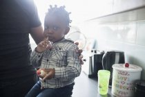 Portrait cute toddler boy eating in kitchen — Stock Photo