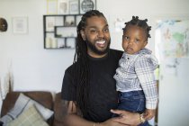 Portrait happy father with long braids holding toddler son — Stock Photo