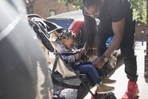 Pai prendendo filho criança em carrinho na calçada ensolarada — Fotografia de Stock