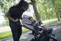 Father pushing toddler son in stroller in park — Stock Photo