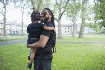 Portrait happy father holding toddler son in park — Stock Photo