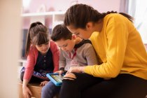 Sisters and brother with Down Syndrome using digital tablet — Stock Photo