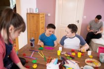 Junge mit Down-Syndrom und Geschwister spielen mit Spielzeug am Tisch — Stockfoto