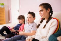 Boy with Down Syndrome watching TV on sofa with sisters — Stock Photo