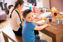 Portrait cute boy with Down Syndrome coloring at table with sister — Stock Photo