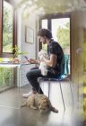Jovem com cães trabalhando na mesa no escritório em casa — Fotografia de Stock